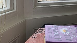 A room corner with a window overlooking a cityscape and a table with a book titled "All Your Love". - Relax Inn Guest House (Brighton)
