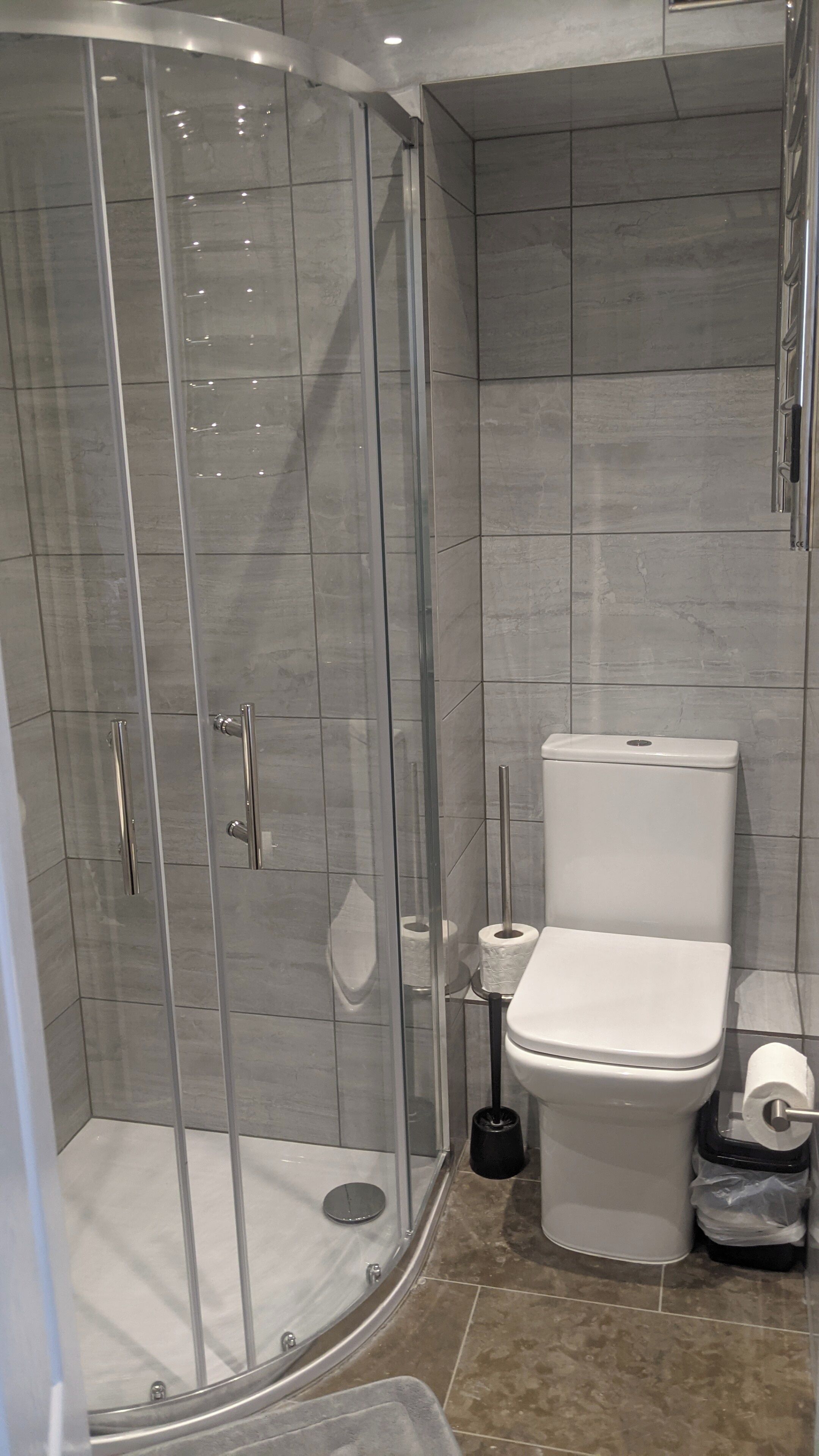 A modern bathroom with a glass-enclosed shower, a toilet, and a bidet.