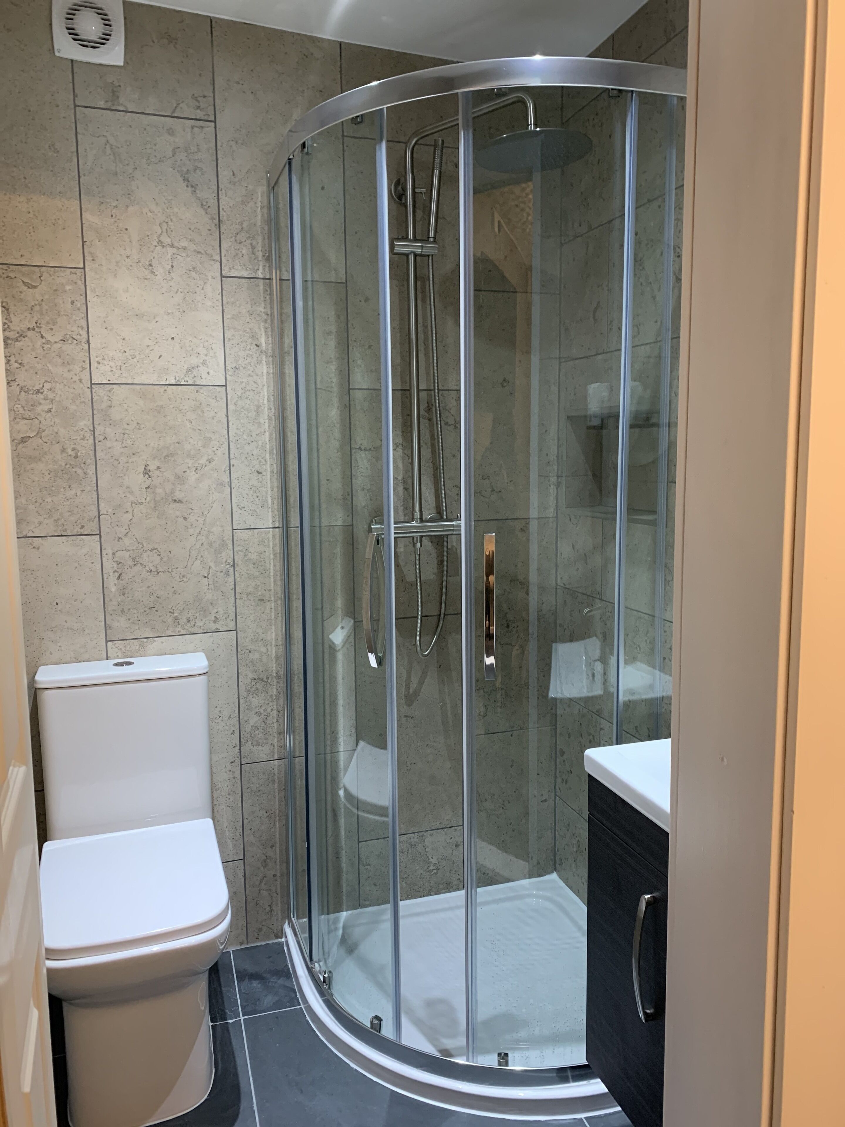 Un baño moderno con ducha acristalada, inodoro y tocador.