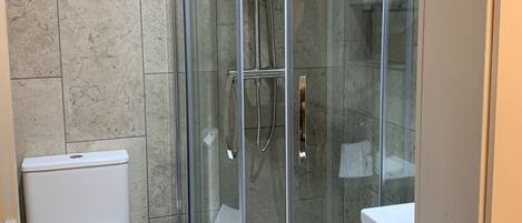 Un baño moderno con ducha acristalada, inodoro y tocador.