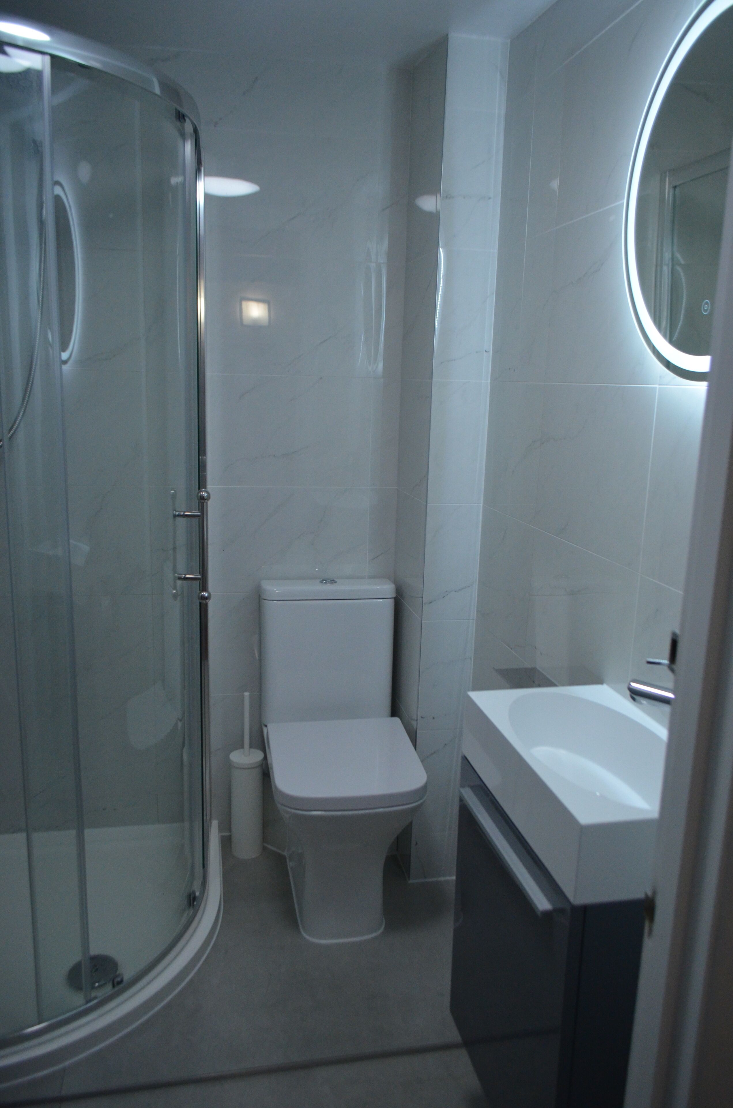 A compact bathroom with a glass-enclosed shower, a toilet, and a sink.