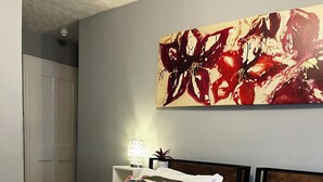 A hotel room with two beds, each with white linens and decorative pillows, a red blanket, and a wall-mounted artwork. - Relax Inn Guest House (Brighton)