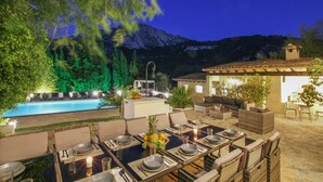 An outdoor dining area with a pool and mountain backdrop.