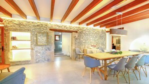 A dining area with a stone wall, wooden beams, and a table with chairs.
