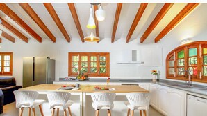 A modern kitchen with wooden beams, white cabinets, and a central island with bar stools.