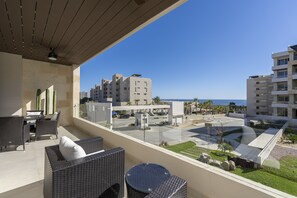 Ein Balkon mit Korbmöbeln, Blick auf einen Parkplatz und Gebäude im Hintergrund.