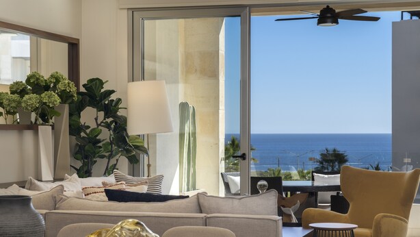 A modern living room with a sofa, a coffee table, and a view of the ocean.
