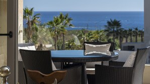 A balcony with wicker furniture, a glass door, and a view of the ocean.