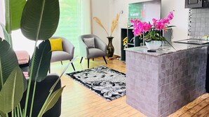 Une cuisine moderne avec un îlot central gris, un téléviseur à écran plat et une orchidée en pot.