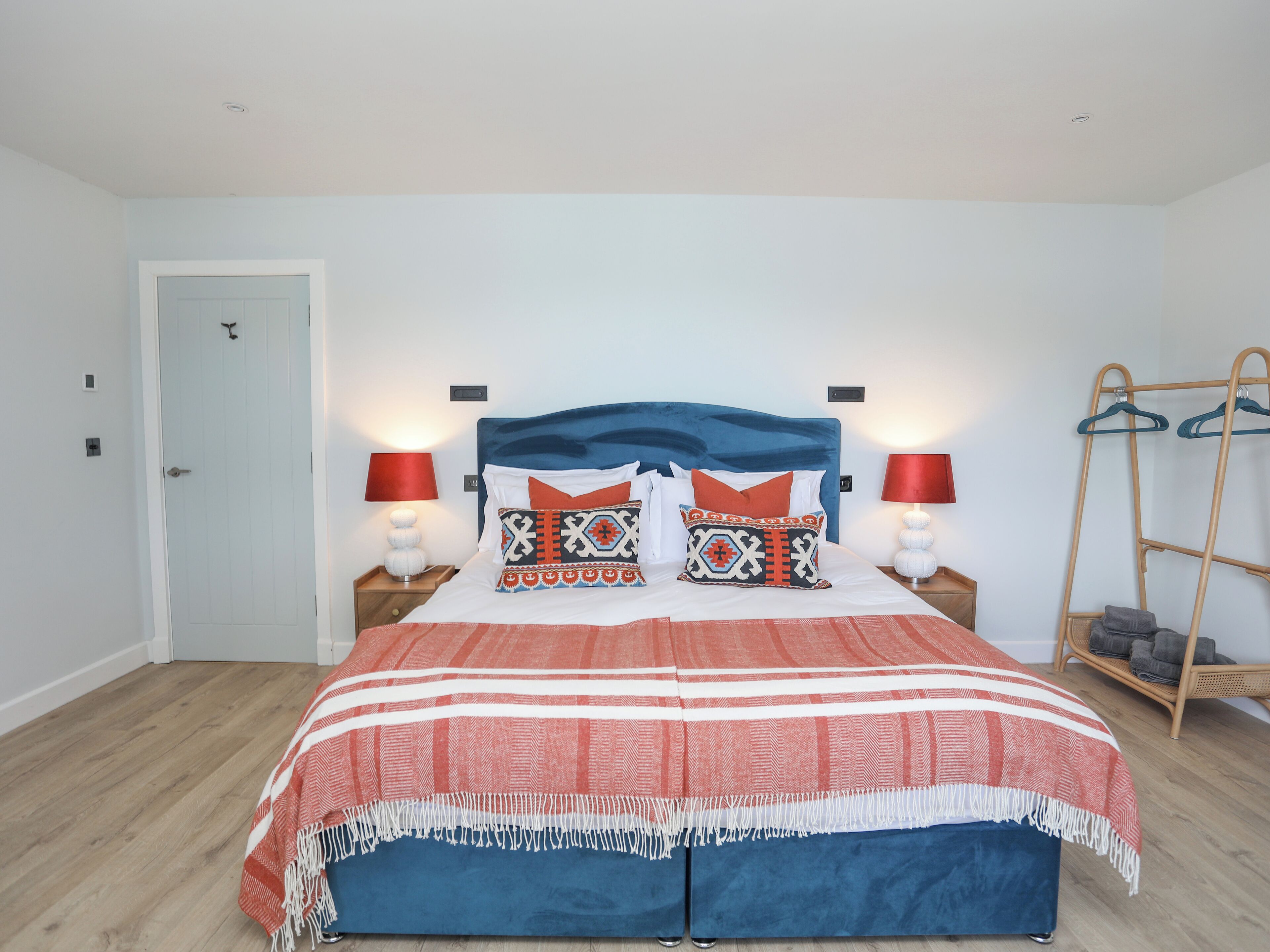 Une chambre bien rangée, avec un lit, deux tables de chevet, une échelle en bois et une porte.