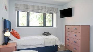 Un dormitorio con dos camas, un aparador, un televisor y una ventana con persianas.