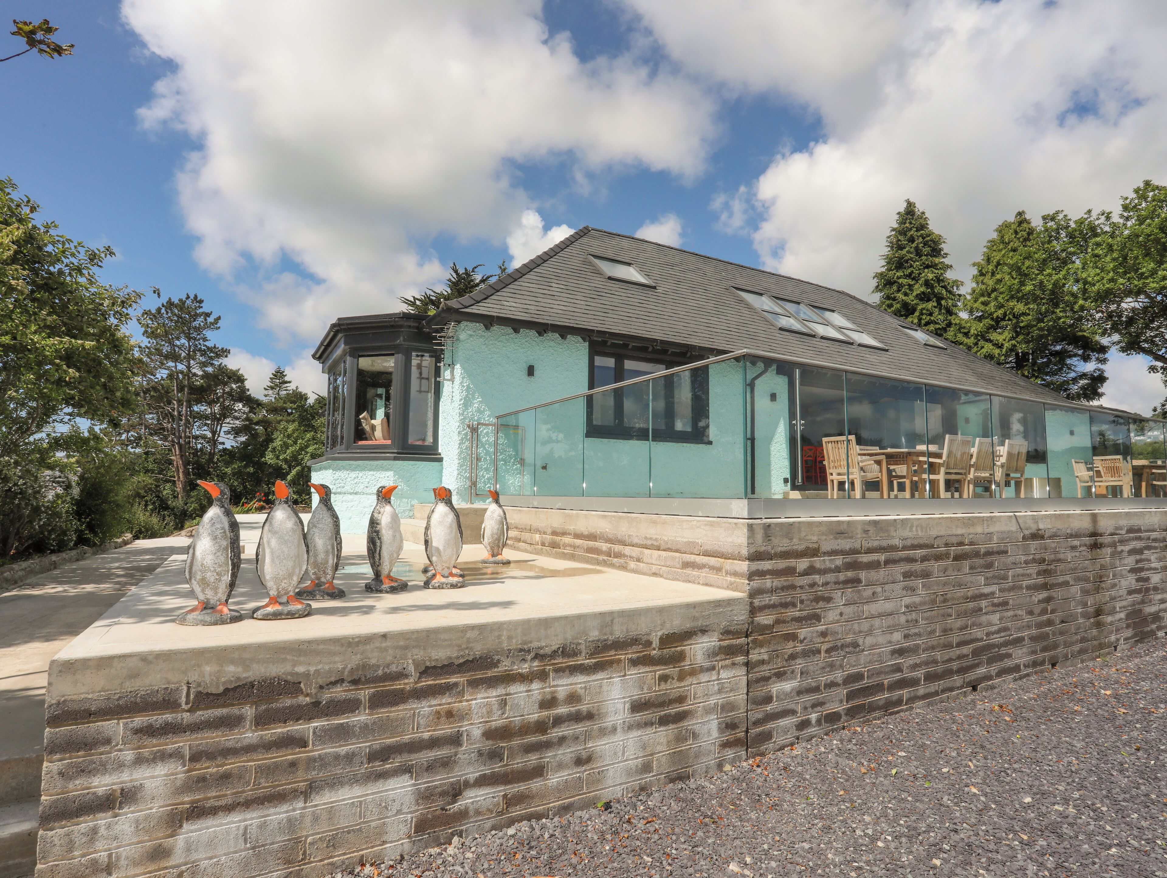 A modern building with a glass facade, a stone retaining wall, and outdoor seating.