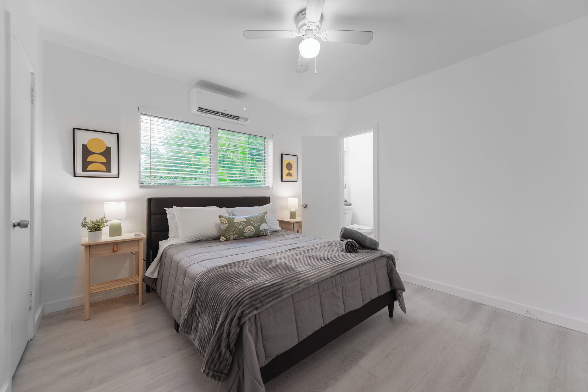 A bedroom with a bed, bedside tables, a ceiling fan, and a window with blinds.