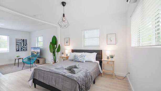 Un dormitorio moderno con una cama grande, un escritorio, una silla y una lámpara colgante.
