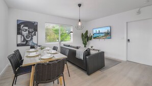 Una sala de estar moderna con comedor, que incluye un sofá, mesa de comedor, sillas y obras de arte en las paredes.