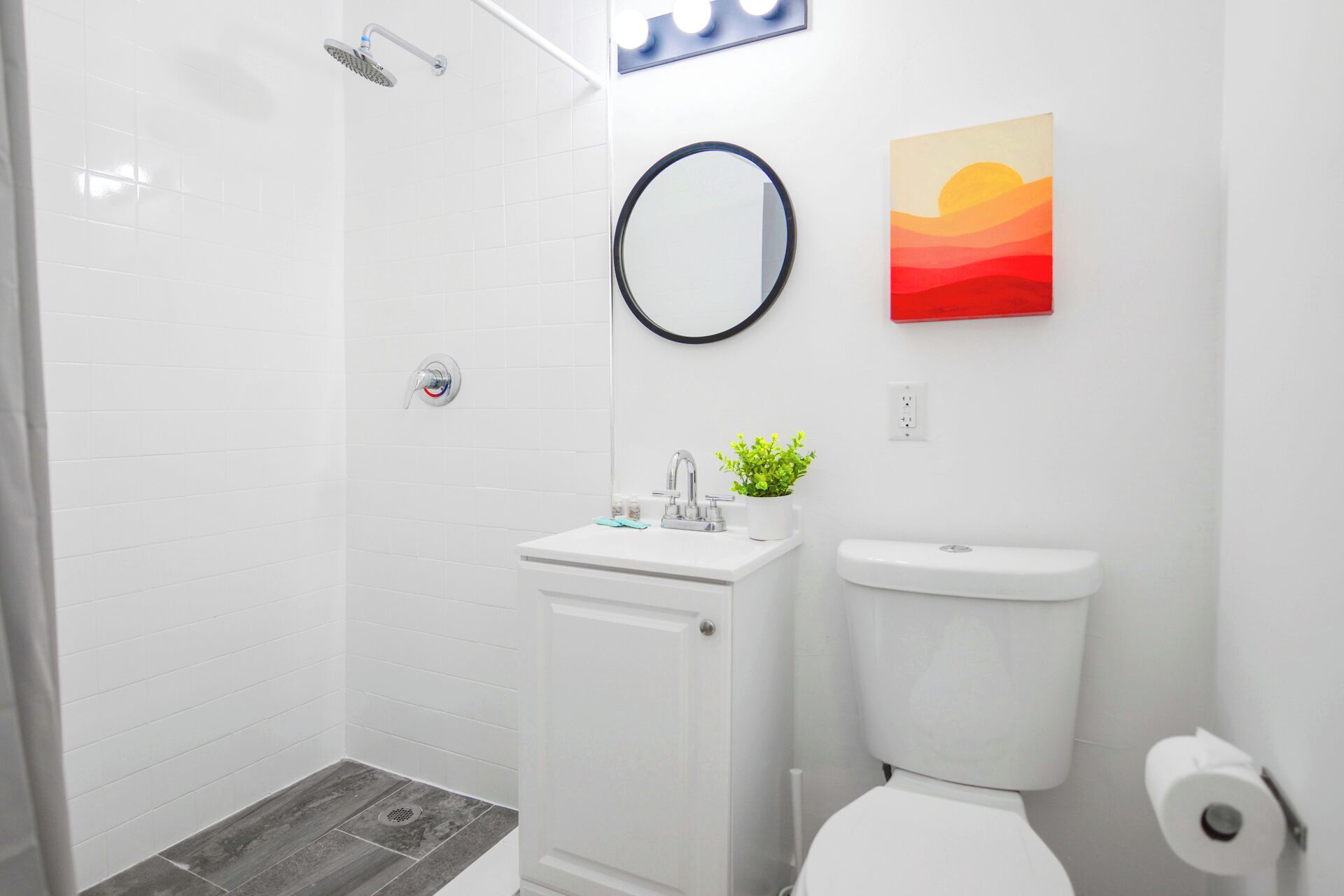 A bathroom with a shower, toilet, sink, and a mirror.