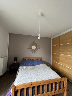 Une chambre à coucher avec un lit en bois, une table de chevet avec une lampe, un miroir et une armoire ornée de panneaux en bois.