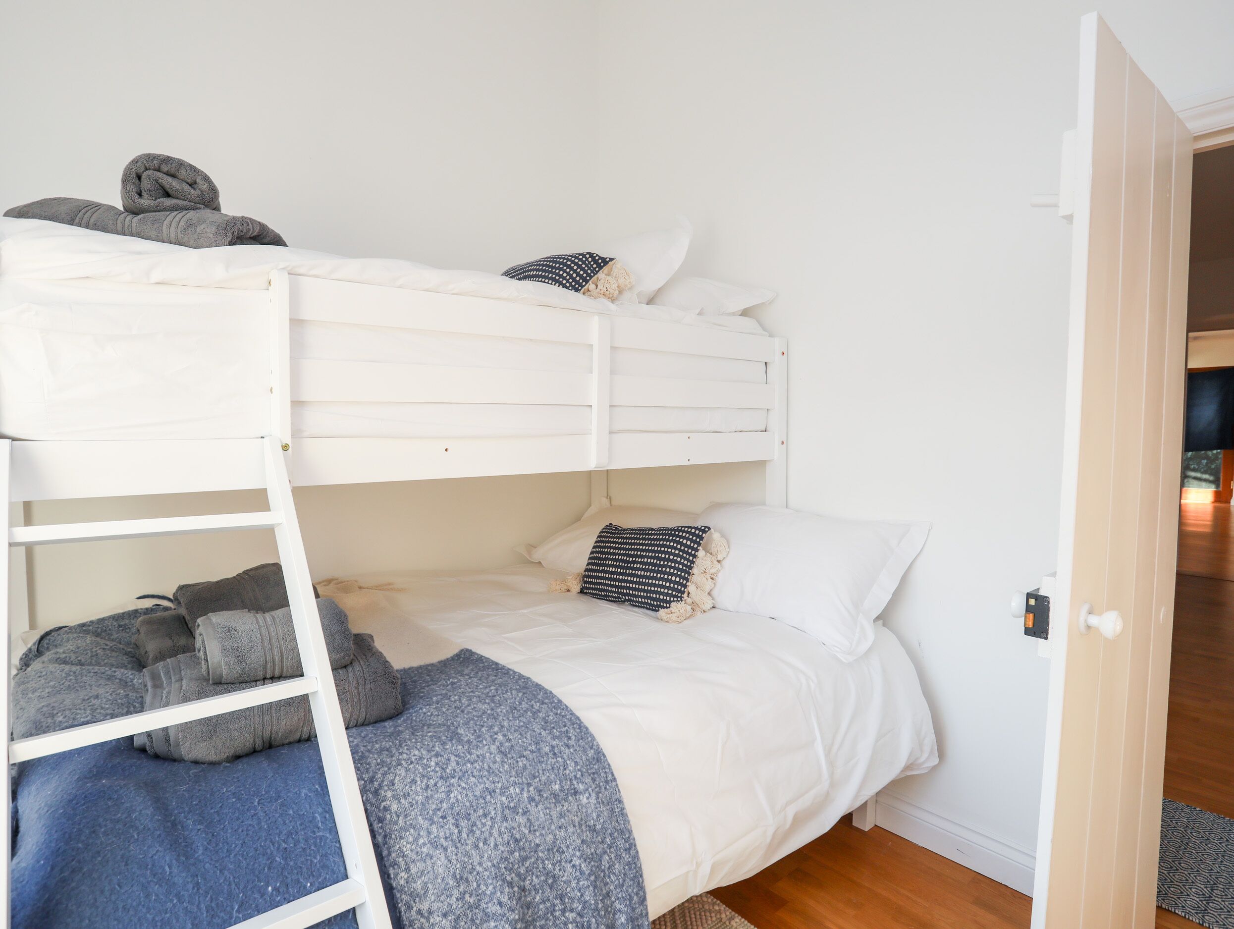 A bunk bed room with a ladder, a blue blanket, and a patterned pillow.