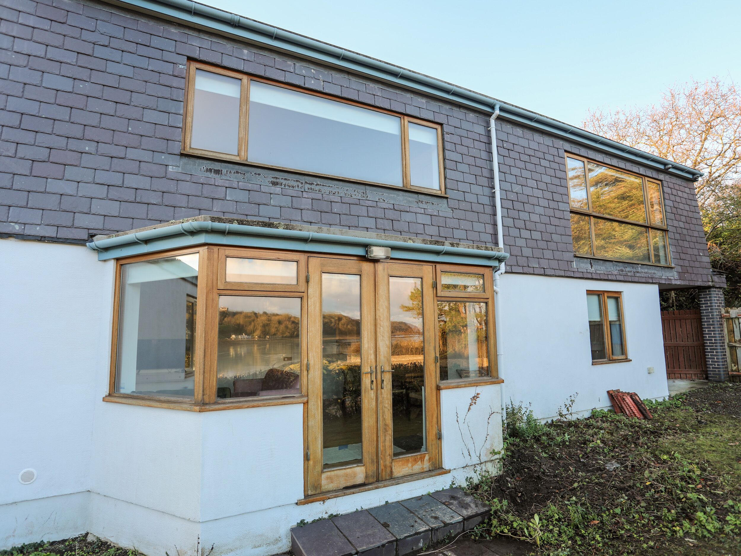 Een woonhuis met twee verdiepingen, een groot erker en een klein portaaltje.