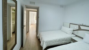 A hotel room with a large mirror, two beds, a bedside table, and a bathroom visible through an open door. - DELUXE CENTER R146 (Benidorm)