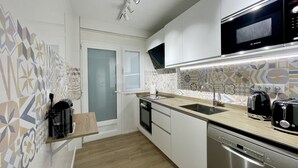 A modern kitchen with white cabinets, a microwave, a coffee maker, and a dishwasher. - DELUXE CENTER R146 (Benidorm)