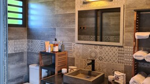 A modern bathroom with a wooden ceiling, a large mirror, a sink, and a toilet. - Les Chambres et table d'hôte du Voyageur/ chambre citronnelle (La Plaine Des Palmistes)