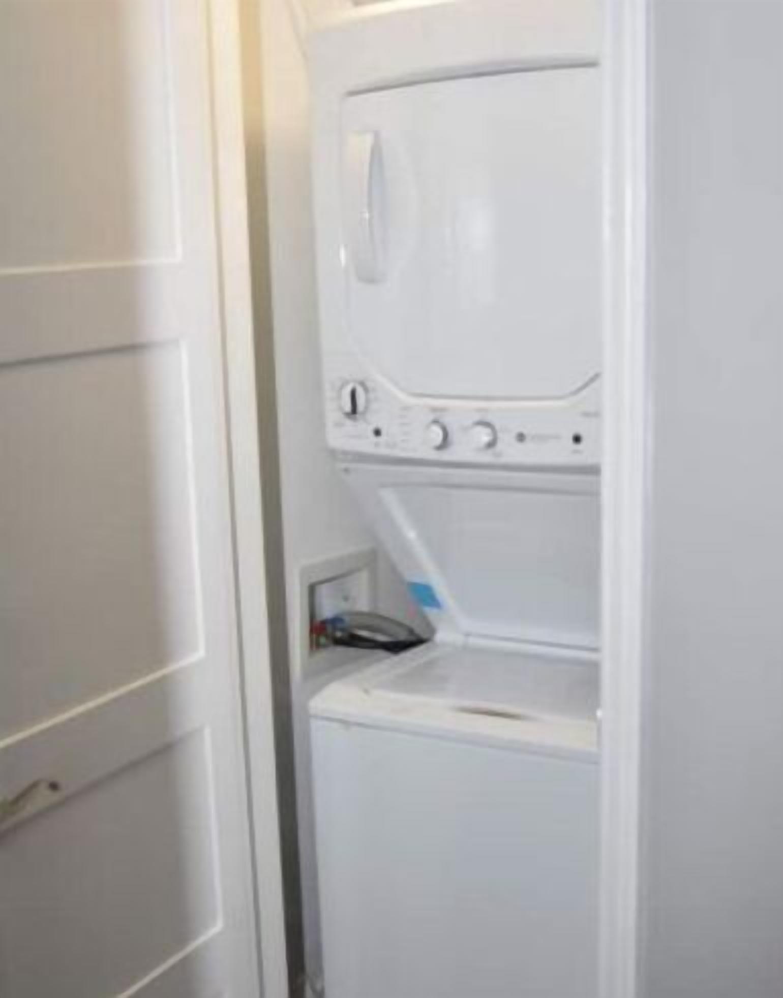 A white washing machine in a compact, enclosed space, likely a utility room or laundry area.
