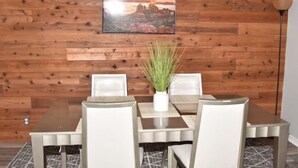 Un coin repas avec un mur en bois, un tableau et une plante en pot.
