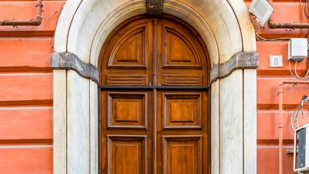 A large wooden double door with a stone archway, set in a building with a red facade. - Ferdinando Art House by Wonderful Italy (Naples)