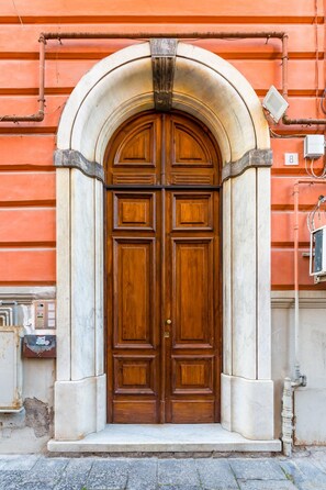 A large wooden double door with a stone archway, set in a building with a red facade. - Ferdinando Art House by Wonderful Italy (Naples)