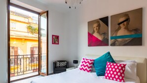 A bedroom with a large bed, a nightstand, a chair, and a view of the outside balcony. - Ferdinando Art House by Wonderful Italy (Naples)