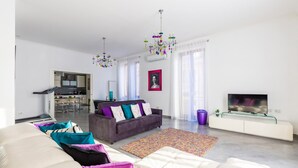 A modern living room with a sofa, a couch, a TV, and a kitchen in the background. - Ferdinando Art House by Wonderful Italy (Naples)