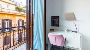 A room with a balcony, a desk with a chair, a framed picture, a lamp, and a small shelf with items. - Ferdinando Art House by Wonderful Italy (Naples)