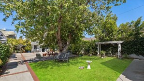 A backyard with a patio, a pergola, and a well-maintained lawn. - Rest Haven Motel (Santa Monica)
