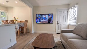 A living room with a television, a sofa, a coffee table, and a dining area with chairs and a table. - Rest Haven Motel (Santa Monica)