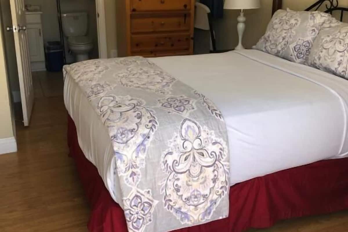 Un dormitorio con una cama grande, cómoda de madera y un espejo.