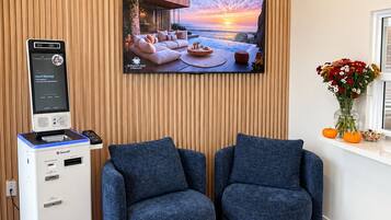 A room with a television displaying a sunset scene, two blue armchairs, a massage chair, and a massage machine.