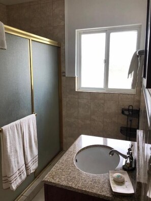 Ein Badezimmer mit Waschbecken, Handtuchhalter, Fenster und Duschbereich.