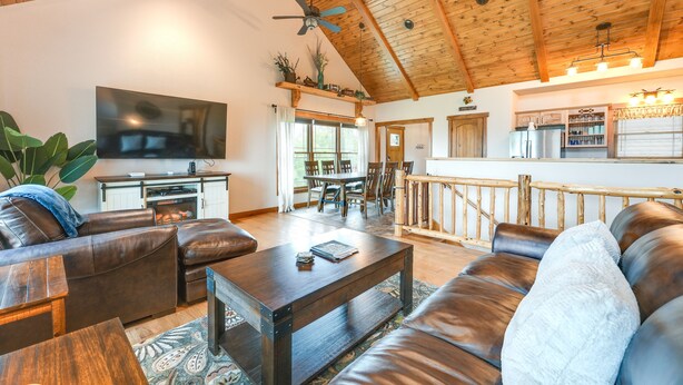 A spacious living area with a high ceiling, leather sofas, a coffee table, and a television. - Water-View Home Half Mile to Table Rock Lake (Green Forest)
