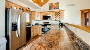 A kitchen with a stainless steel refrigerator, a microwave, a stove, and wooden cabinets. - Water-View Home Half Mile to Table Rock Lake (Green Forest)