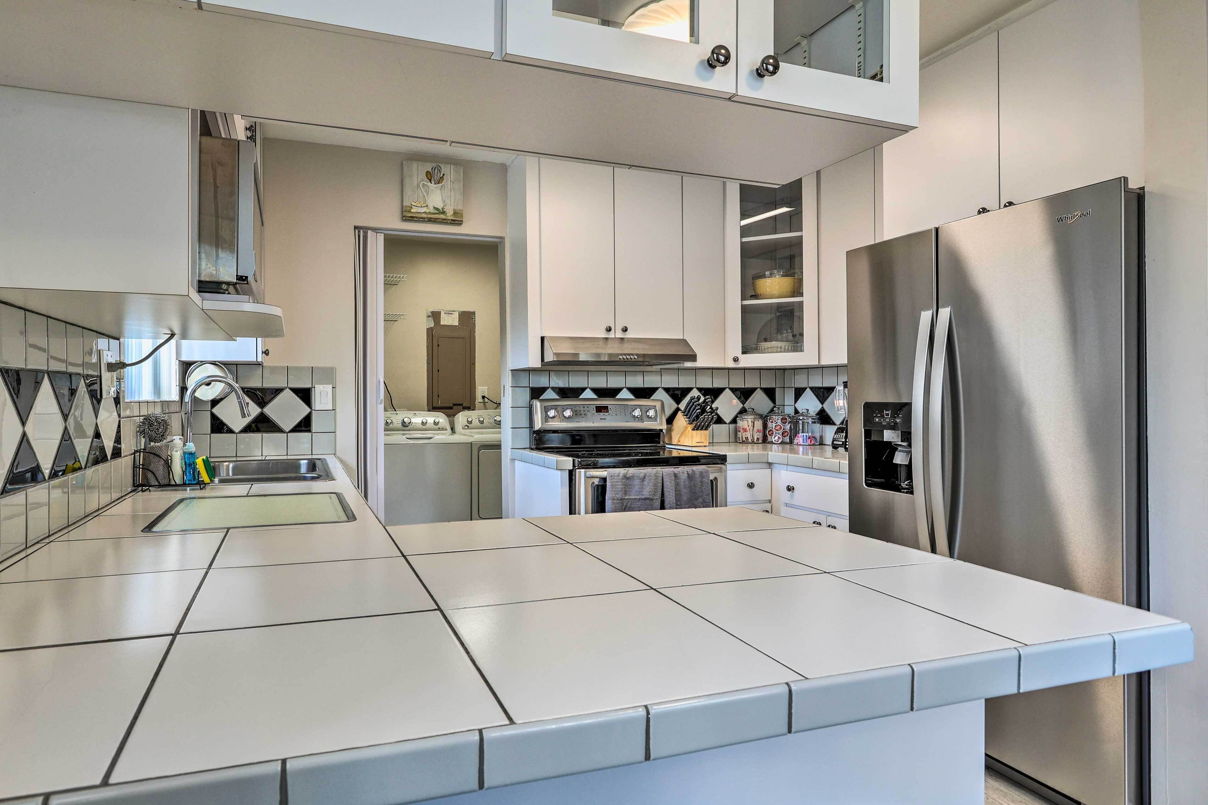 Una cocina moderna con armarios blancos, electrodomésticos de acero inoxidable y un salpicadero de azulejos.