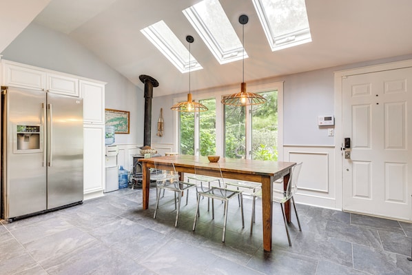 A modern kitchen with a central island, stainless steel appliances, and skylights.