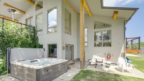 Een modern huis met een jacuzzi, buitenmeubels en grote ramen.