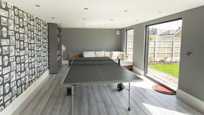 A room with a ping pong table, a sofa, and a wall covered with pictures. - Sunbeam Cottage (Whitstable)