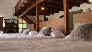 Quarto com cama grande, lareira e estrutura de teto em madeira.