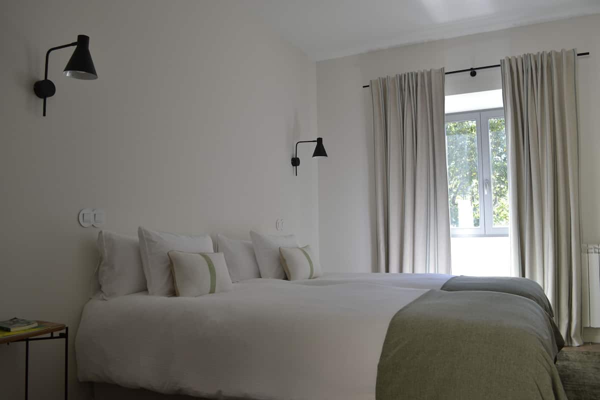 Un dormitorio con una cama grande, dos mesitas de noche y dos lámparas de pared.