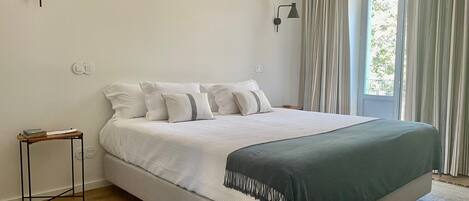Une chambre à coucher moderne avec un grand lit, une table de chevet et deux lampes fixées au mur.