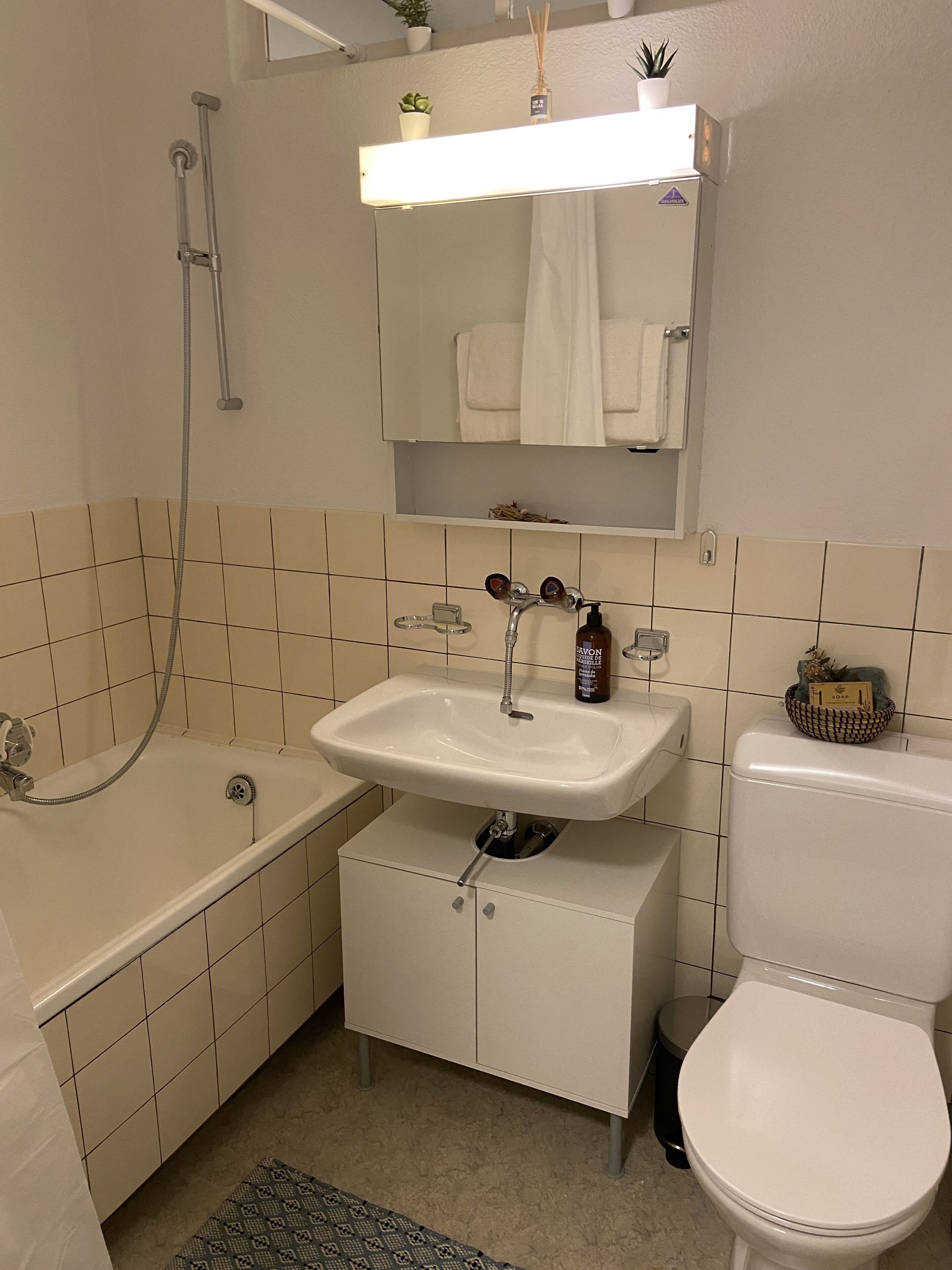 A bathroom with a bathtub, a sink, a toilet, and a mirror above the sink.