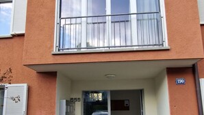 A two-story apartment building with balconies, a ground entrance, and a visible door number. - K190 - 2BDR Apartment close to Zurich Airport (Zürich)