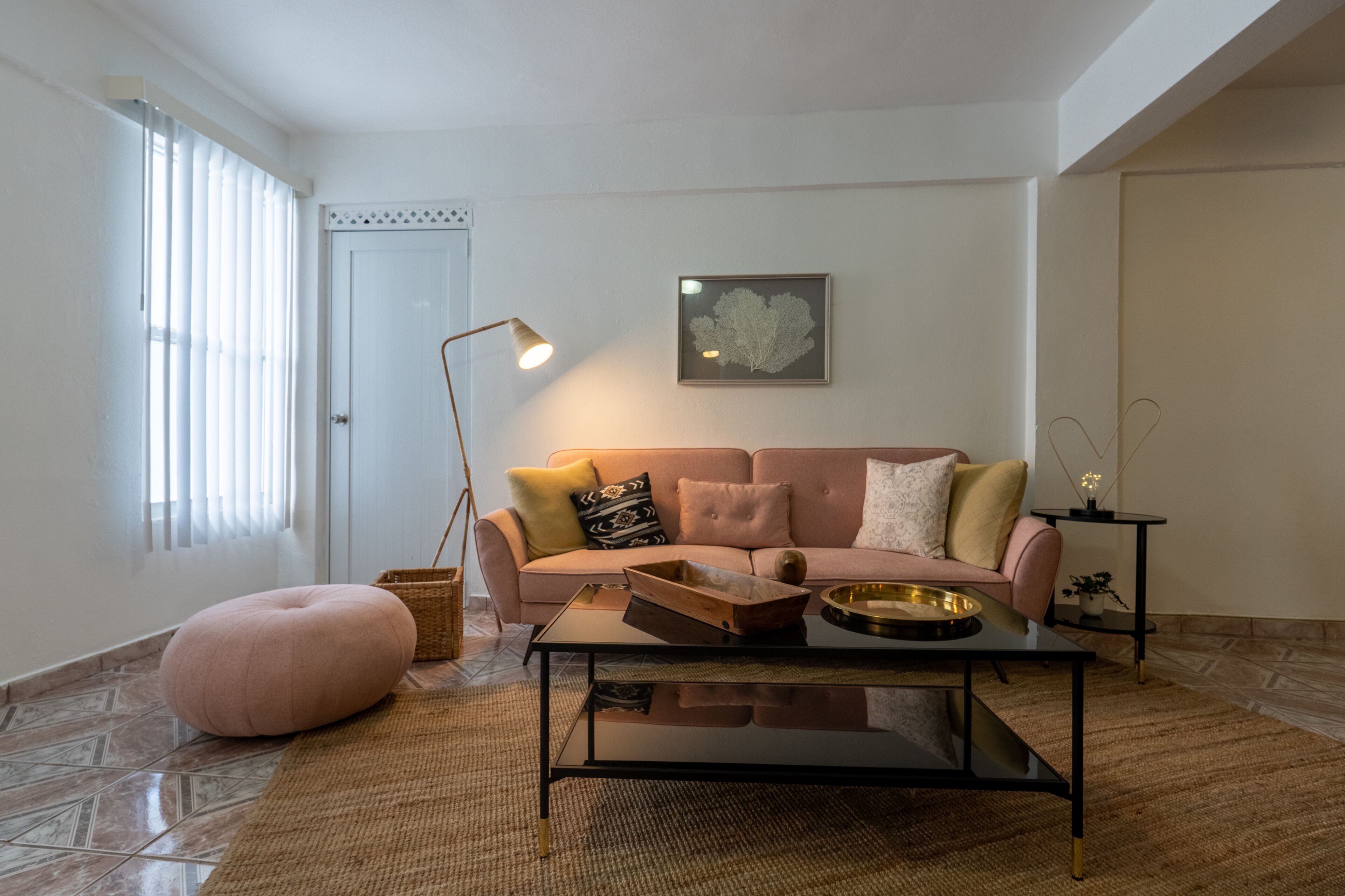 A living room with a sofa, a coffee table, a floor lamp, and a framed artwork on the wall.